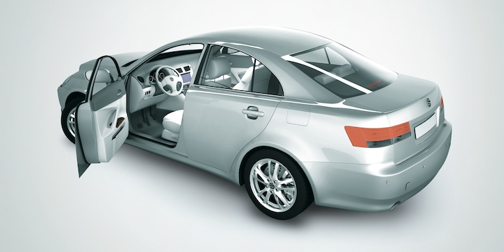 A silver saloon car with an open front left door taken from a rear side angle against a gradient grey background.