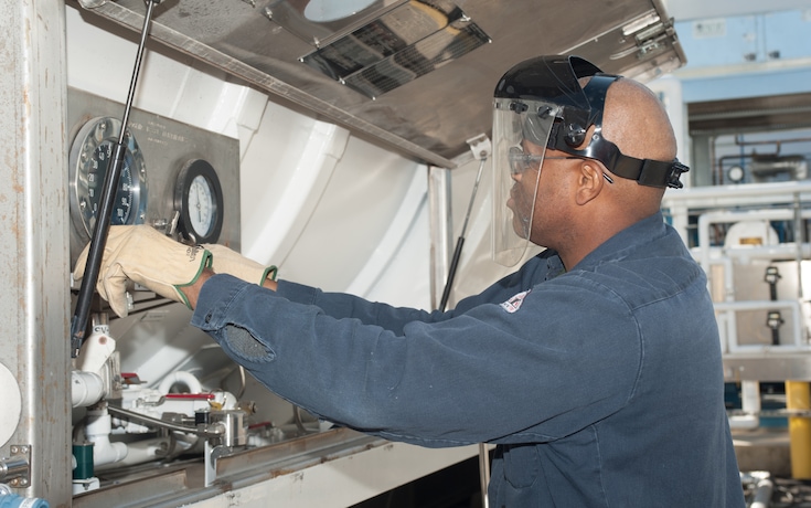 Close-up of operator adjusting and reading gauges at a Linde production plant