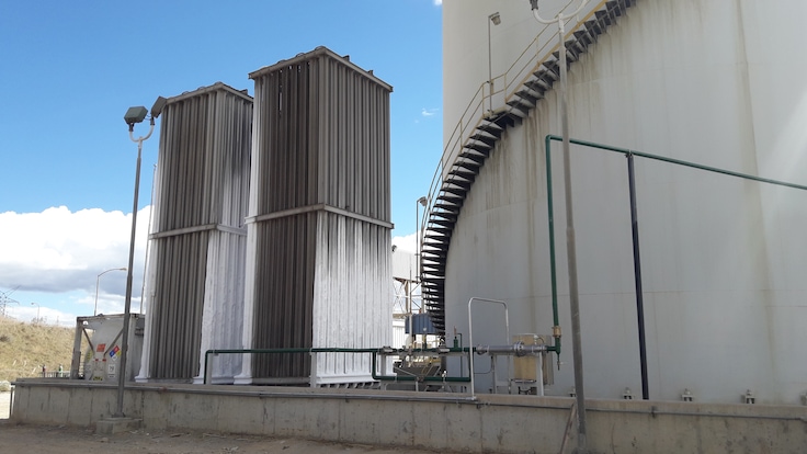 On-site gold mining infrastructure showing two Liquid oxygen vaporizer towers beside one large cylindrical leaching tank.