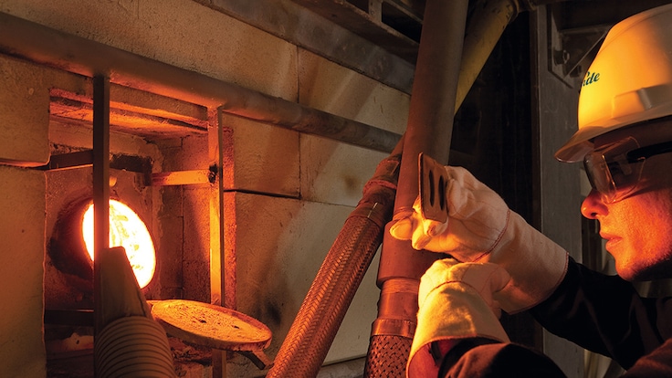 A worker checking flame in glass furnace