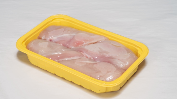 Packaged meat in a yellow plastic tray