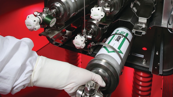 An UpTime gas cylinder being arranged by a worker in white gloves in a semiconductor fab.