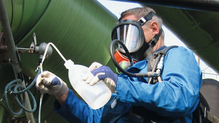 A worker taking a sample for testing at a Claus plant