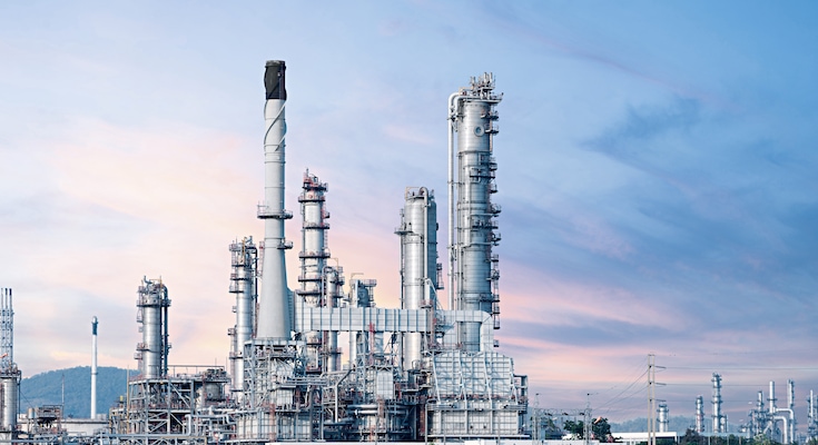 A sulfur recovery site with yellow piles of sulfur outside against the backdrop of emission tower